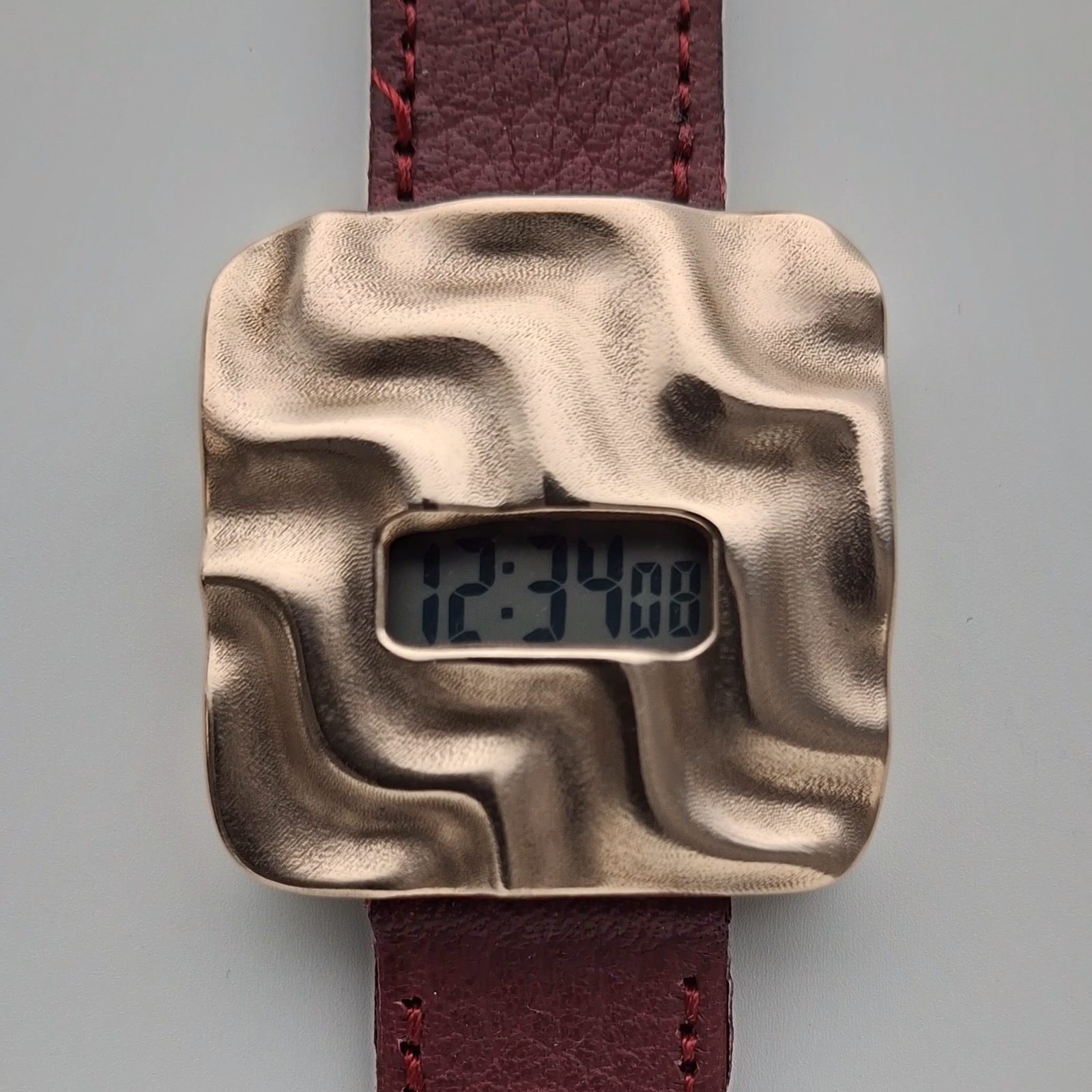 Askja: a small digital display set in an undulating bronze case