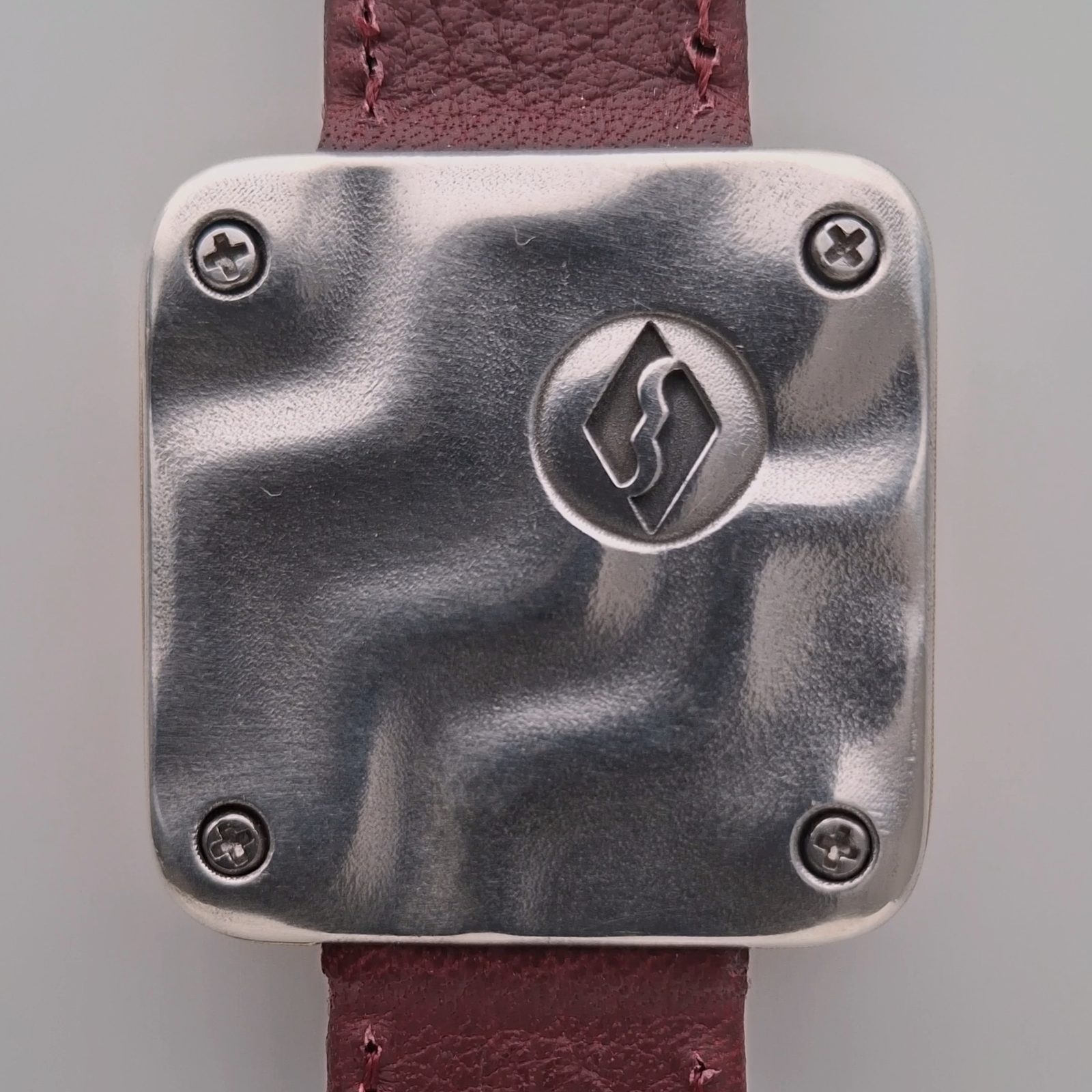 Askja's polished sterling silver caseback with four screws and the Salmiac mark: a raised S within a diamond outline, set in a circular recess
